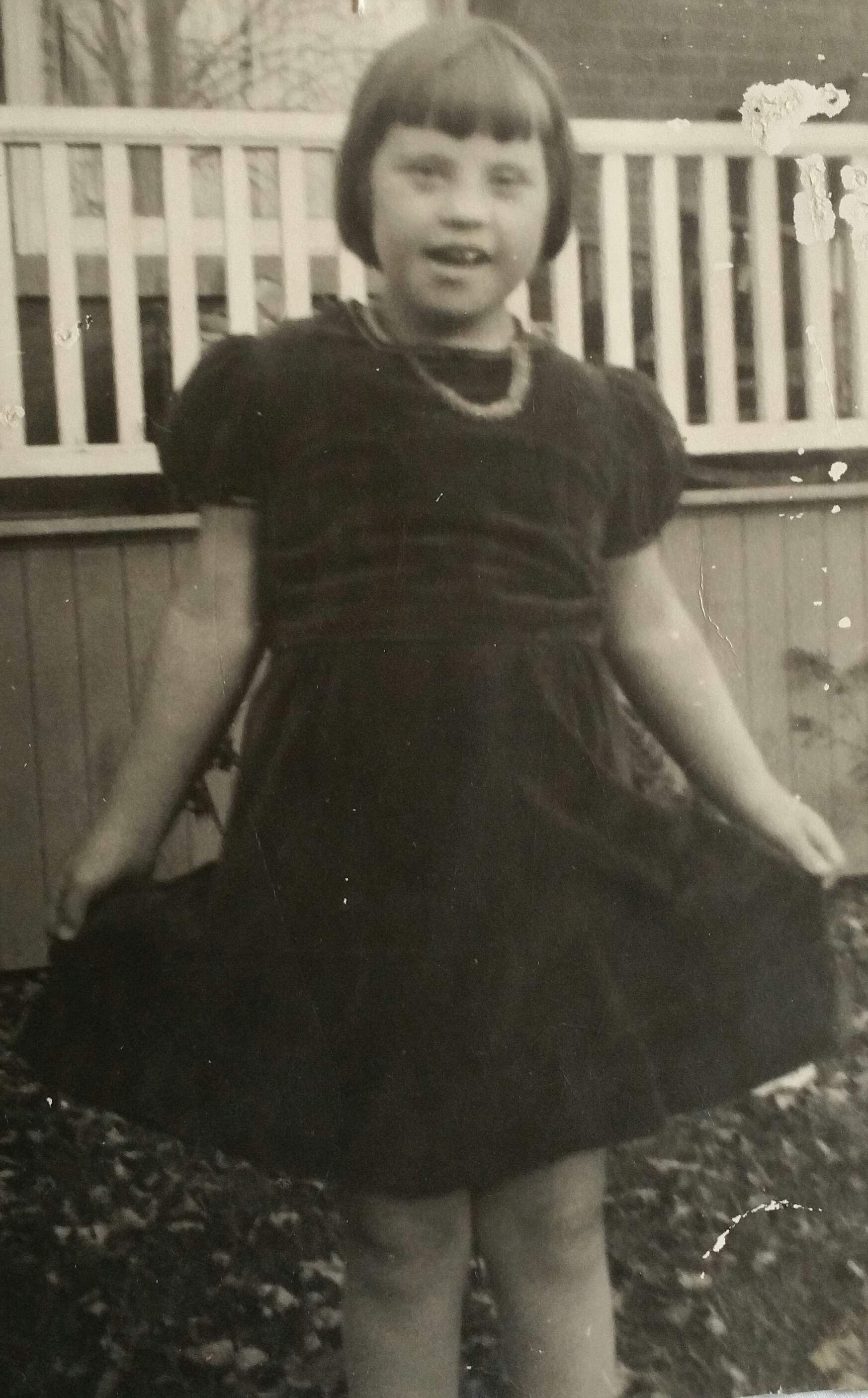 young girl showing off new dress on front lawn with house in background image